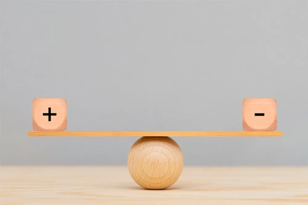 wooden seesaw with plus and minus cubes balanced on opposites ends