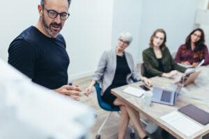 male professional standing in conference room demonstrating to a group